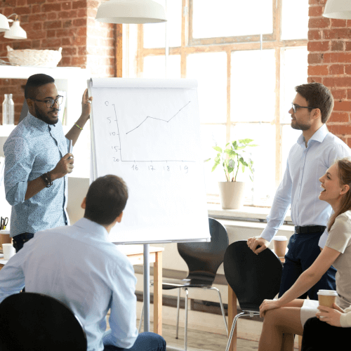 Professional presentation in an office with a team member explaining a graph to attentive colleagues