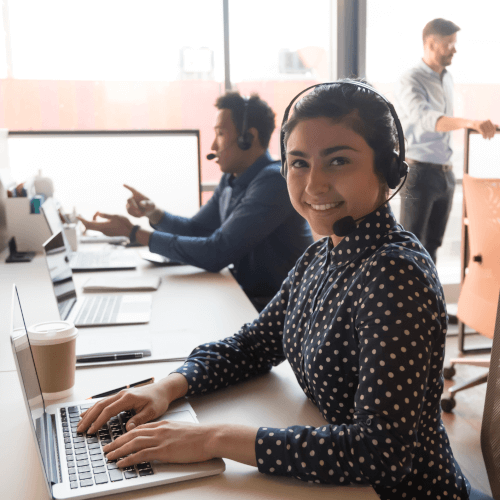 Efficient and cheerful customer service representative with a headset working at her computer