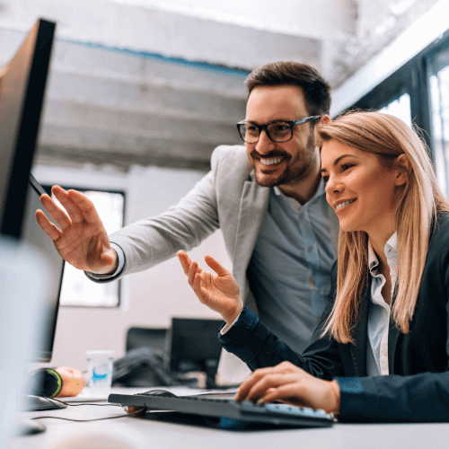 Two colleagues collaborating and discussing payroll software on a computer in an office environment