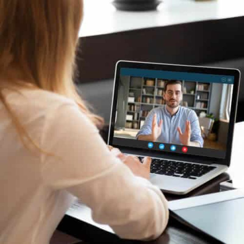 Employer listening to an applicant during a job interview using webcam and laptop